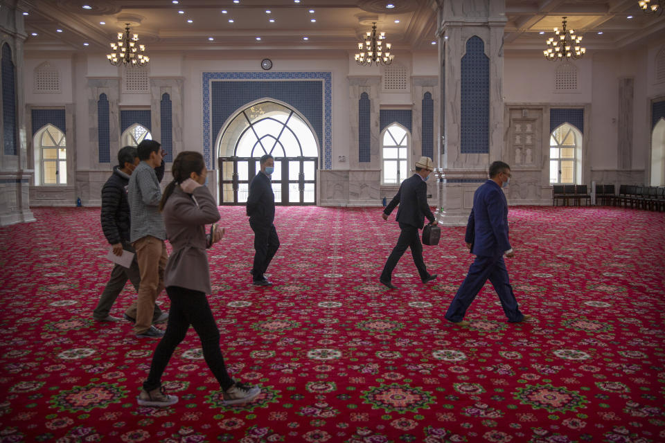 Abit Qazbay, right, an instructor at the Xinjiang Islamic Institute, and government officials walk through the prayer hall during a government organized visit for foreign journalists at the institute's campus in Urumqi in western China's Xinjiang Uyghur Autonomous Region, on April 22, 2021. Under the weight of official policies, the future of Islam appears precarious in Xinjiang, a remote region facing Central Asia in China's northwest corner. Outside observers say scores of mosques have been demolished, which Beijing denies, and locals say the number of worshippers is on the decline. (AP Photo/Mark Schiefelbein)