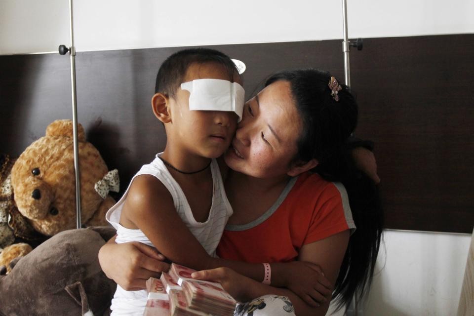 RNPS - PICTURES OF THE YEAR 2013 - A six-year-old boy, whose eyes were gouged out, is cuddled by his mother, who is holding onto donations from the public, at a hospital in Taiyuan, Shanxi province September 3, 2013. Chinese police suspect the boy's aunt of gouging out his eyes, Xinhua state news agency said, then the latest twist in the investigation of a crime that shocked the country. REUTERS/Stringer (CHINA - Tags: CRIME LAW TPX) CHINA OUT. NO COMMERCIAL OR EDITORIAL SALES IN CHINA