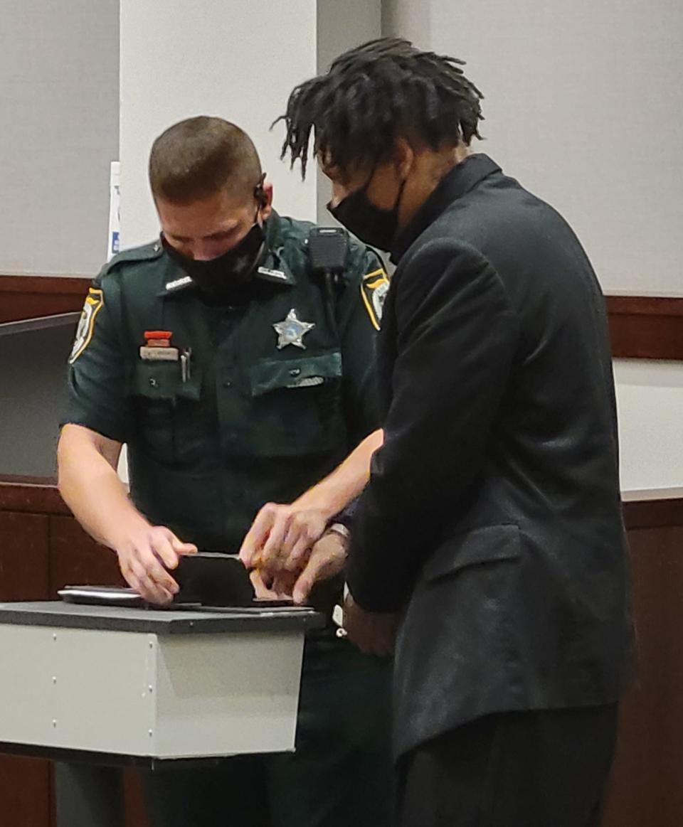 A Bay County Sheriff's deputy takes fingerprints from Andre Bivins after Bivins was convicted in the March 2019 shooting death of Edward Ross, a Panama City Beach man.