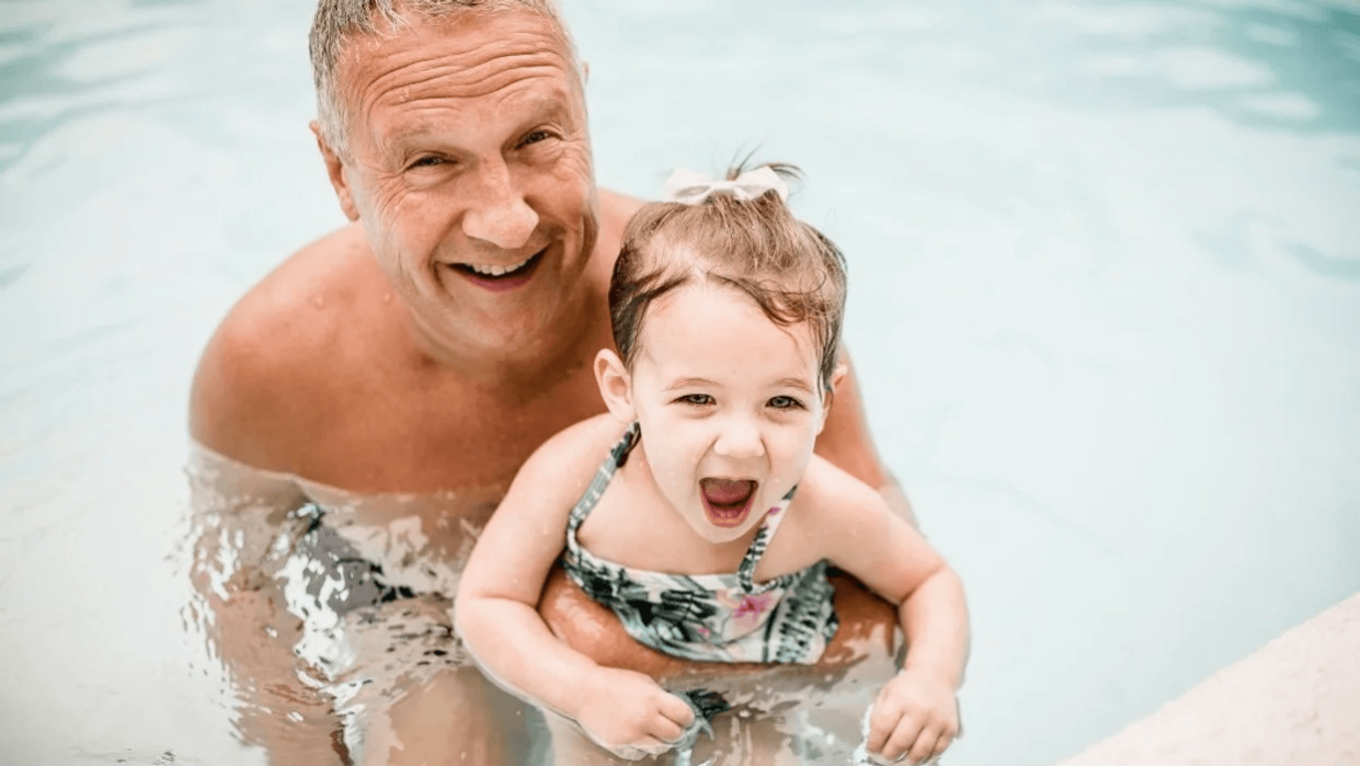 grandpa holding granddaughter in pool