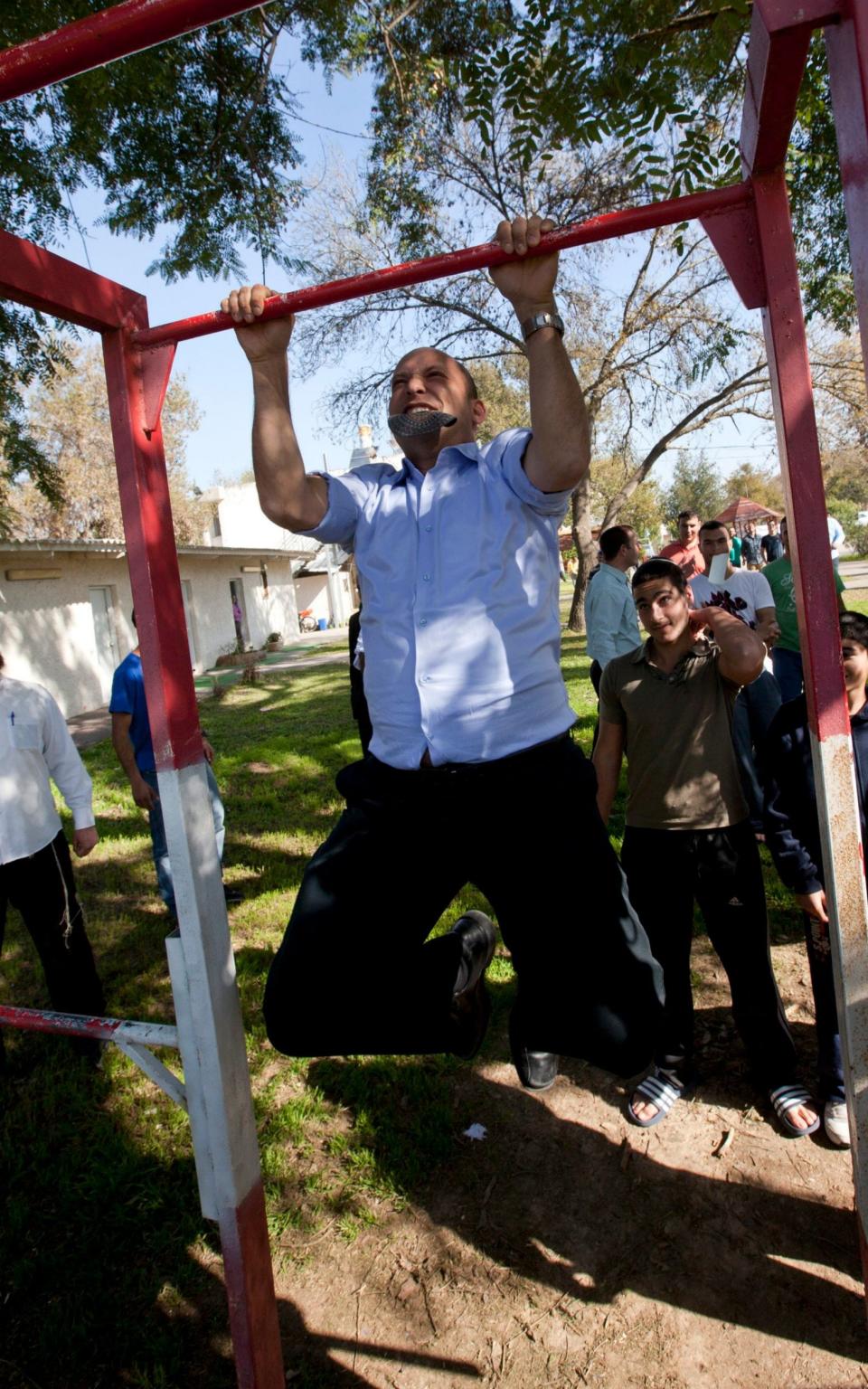 Naftali Bennet doing chin-ups during a 2013 election campaign visit to a religious seminary, where he urged them to settle in religious areas in the West Bank - JIM HOLLANDER /EPA