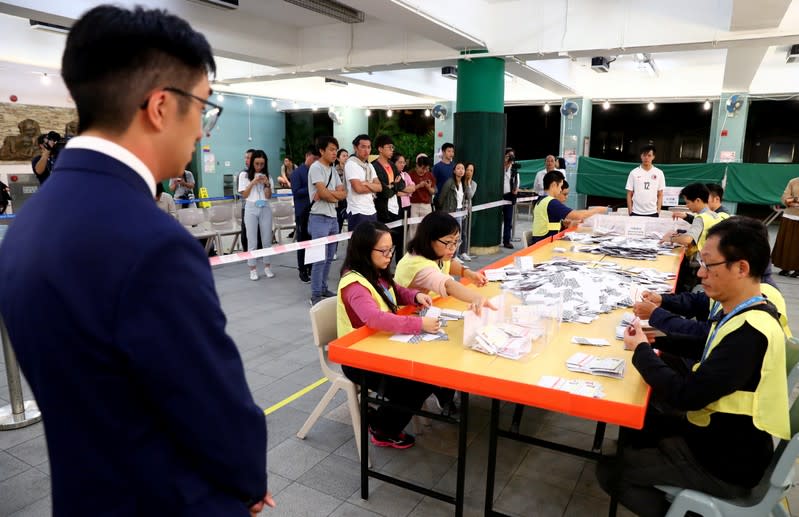 A local candidate looks at officials counting votes at a polling station in Kowloon Tong, Hong Kong