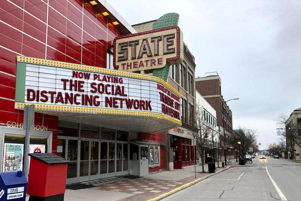 In this March 18, 2020, photo, a tongue-in-cheek message is displayed on the marquee of the State Theatre in Traverse City, Mich. The historic theater hosts the Traverse City Film Festival, led by documentary filmmaker Michael Moore, which is among many summer festivals and events in the tourist-friendly community that have been canceled because of the coronavirus. With summer vacation season looming, this town on a Lake Michigan bay normally would be expecting a crush of visitors. But some local residents have mixed feelings about crowds descending on the area, which might cause the number of virus cases to rise. (AP Photo/John Flesher)