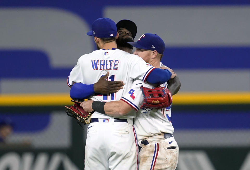 Texas Rangers' Eli White (41), Adolis Garcia, center, and Kole Calhoun, right, celebrate the team's 10-5 win in a baseball game against the Los Angeles Angels, Tuesday, May 17, 2022, in Arlington, Texas. (AP Photo/Tony Gutierrez)