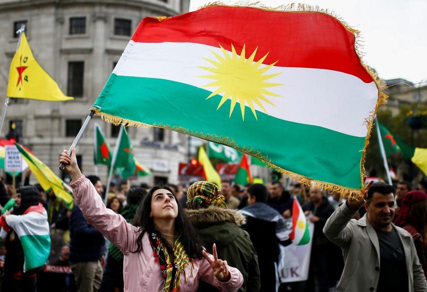 A woman flashes a V-sign as she waves a Kurdish flag during a pro-Kurdish rally against Turkey's military action in northeastern Syria, in London: REUTERS