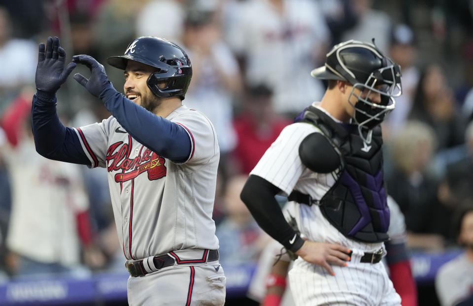 Atlanta Braves'Travis d'Arnaud, left, celebrates as he crosses home plate after hitting a grand slam as Colorado Rockies catcher Brian Serven looks away in the fifth inning of a baseball game Thursday, June 2, 2022, in Denver. (AP Photo/David Zalubowski)