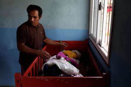 Tulio Medina, father of Eliannys Vivas, who died from diphtheria, puts clothes on a cot at his home in Pariaguan, Venezuela January 26, 2017. REUTERS/Marco Bello