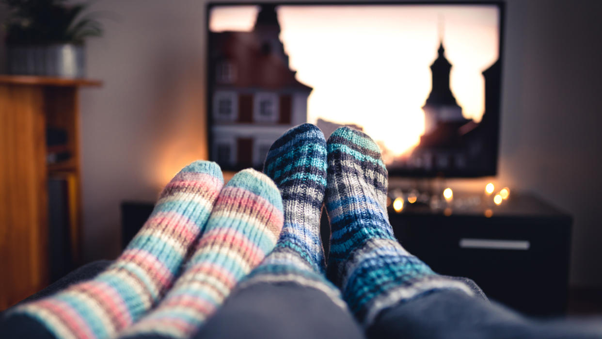 Couple with socks and woolen stockings watching movies or series on tv in winter.