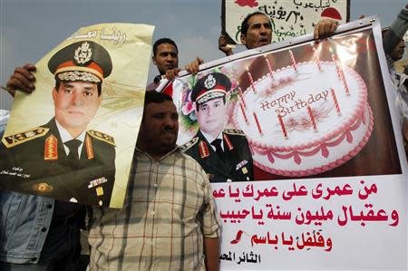 Supporters of Egypt's army chief General Abdel Fattah al-Sisi celebrate Sisi's birthday during a rally at Tahrir square in downtown Cairo, November 19, 2013, to commemorate the second anniversary of the deaths of 42 people in clashes with security forces on Mohamed Mahmoud Street nearby. The sign on right reads, "We wish you a million returns". REUTERS/Mohamed Abd El Ghany