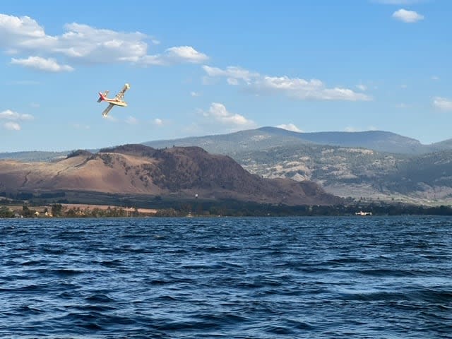 Planes scooped water on the American side of Osoyoos Lake on July 29, 2023 as a wildfire originating in Washington state grew over the border with Canada prompting an evacuation alert for Osoyoos.