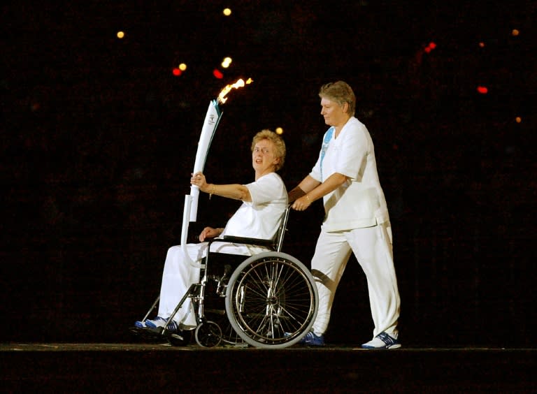 Olympic running legend Betty Cuthbert (L), winner of four gold medals in 1956 and 1964, is escorted by Reelene Boyle as she holds the Olympic torch during the opening ceremony of the 2000 Summer Olympics in Sydney