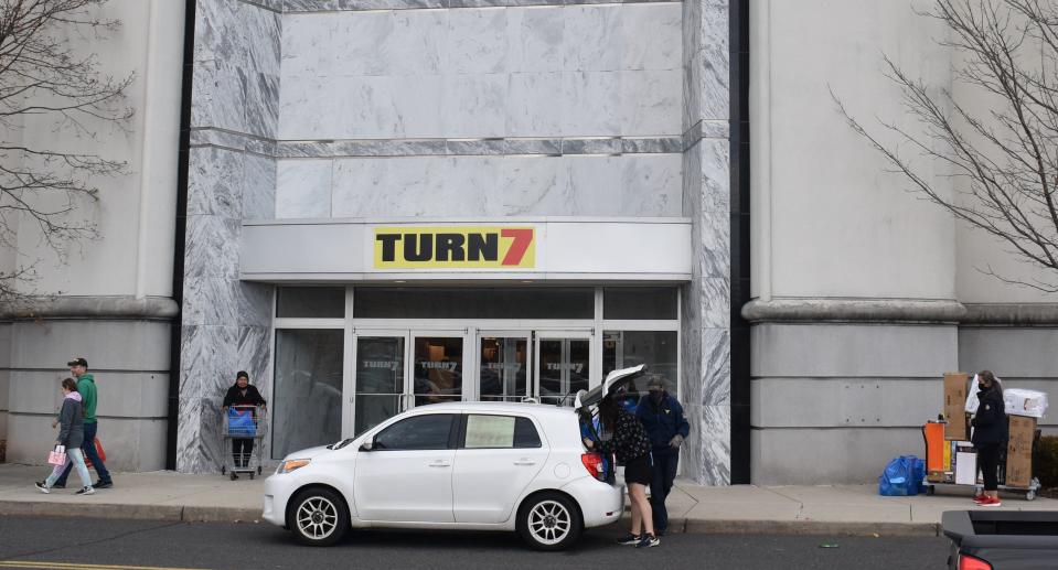 Shoppers carry purchases from a Turn 7 discount store that opened Thursday at Moorestown Mall.