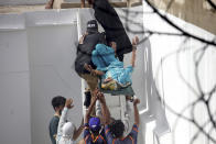 Volunteers carry an injured person at the site of a plane crash in Karachi, Pakistan, Friday, May 22, 2020. An aviation official says a passenger plane belonging to state-run Pakistan International Airlines carrying more than 100 passengers and crew has crashed near the southern port city of Karachi. (AP Photo/Fareed Khan)