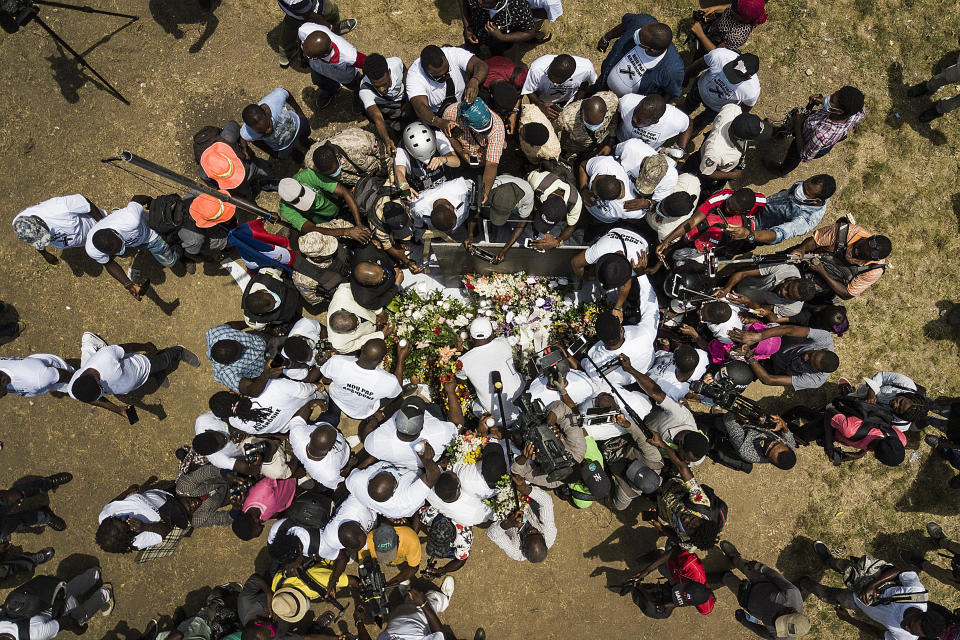 Members of the press gather around supporters of slain President Jovenel Moise bringing flowers, cigars, candles and prayer to create a memorial outside the presidential palace in memory of slain President Jovenel Moise in Port-au-Prince, Haiti, Wednesday, July 14, 2021. Moise was assassinated on July 7. (AP Photo/Matias Delacroix)