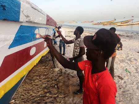 Men paint a fishing boat on a beach in Dakar, Senegal November 28, 2018. REUTERS/ Edward McAllister