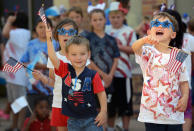 <p>Carrie Baeza, left, Wyatt Cross, center, and Graysen Ziegler wave flags as they sing “Wave Your Flag” during an annual patriotic program Friday, June 30, 2017 during Summer Day Camp at Odessa Christian School in Odessa, Texas. A parade of decorated bicycles and tricycles followed the program. (Photo: Mark Sterkel/Odessa American via AP) </p>