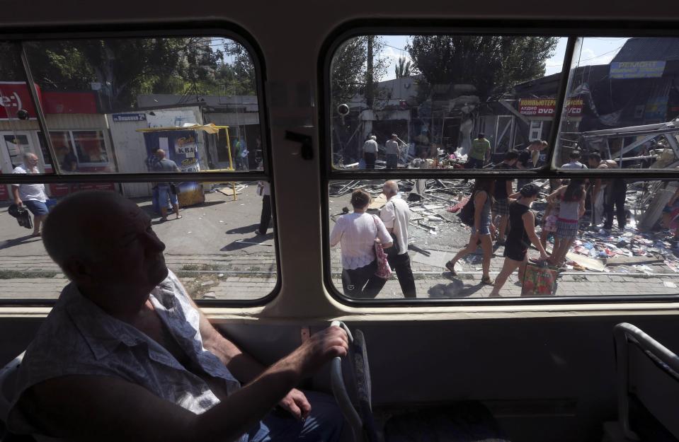 A man sits in a tram as people gather near a damaged building following what locals say was a recent airstrike by Ukrainian forces in Donetsk, August 6, 2014. REUTERS/Sergei Karpukhin (UKRAINE - Tags: MILITARY CONFLICT CIVIL UNREST TRANSPORT POLITICS)