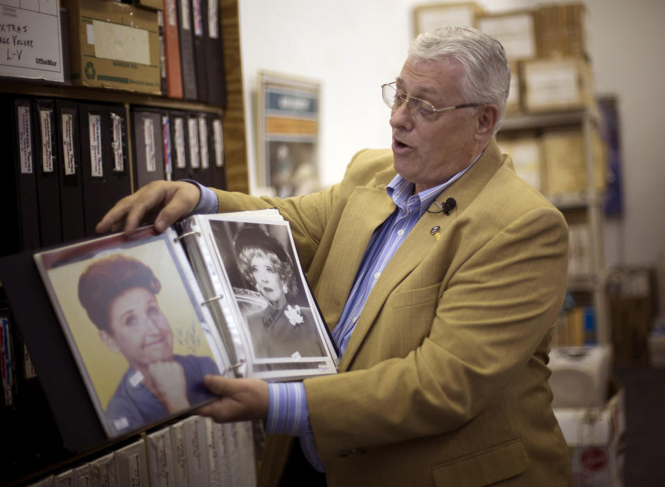 In this Friday, Oct. 19, 2012 photo, memorabilia collector Ken Kallin shows off autographed photos of Ann B. Davis, left, and Betty Davis, at his Oakland Park, Fla. office. Three decades ago, Kallin began amassing 120,000 pieces in a memorabilia collection that includes photographs signed by Muhammad Ali and Neil Armstrong along with rare books and trading cards. By the end of Saturday, Oct. 27, 2012 he's hoping to have gotten rid of nearly all of it _ at an auction to benefit his daughter, who suffers from a rare autoimmune disease that makes her bones dangerously brittle and causes her body's defenses to attack her own blood vessels. (AP Photo/J Pat Carter)