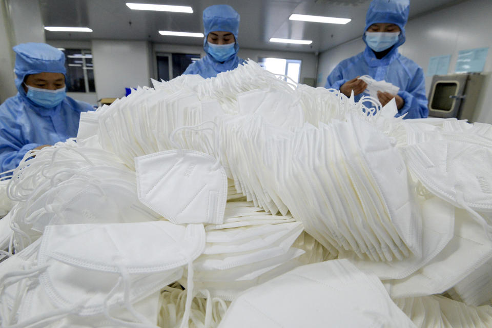 Workers wearing face masks to protect themselves from the coronavirus arrange the face masks at a factory in Handan city in north China's Hebei province on Jan. 8, 2021. China's economy grew 2.3% in 2020 as a recovery from the coronavirus pandemic accelerated while the United States, Europe and Japan struggled with disease flare-ups. (Chinatopix via AP)