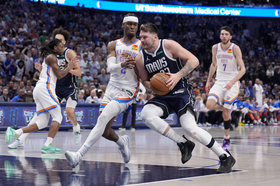 Dallas Mavericks guard Luka Doncic, center right, drives to the basket as Oklahoma City Thunder's Shai Gilgeous-Alexander (2) defends in the second half in Game 4 of an NBA basketball second-round playoff series Monday, May 13, 2024, in Dallas. (AP Photo/Tony Gutierrez)