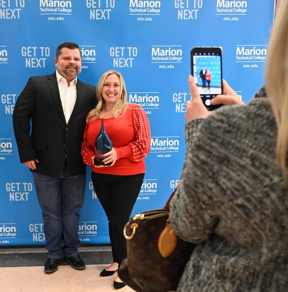 James and Lyndsey Vance smile while Blair Rowland captures a photo after the induction.