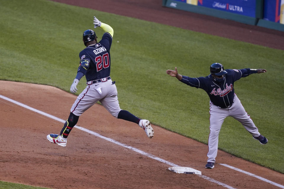 Atlanta Braves' Marcell Ozuna celebrates his grand slam with first base coach Eric Young Sr. during the third inning of the team's baseball game against the Washington Nationals at Nationals Park, Wednesday, May 5, 2021, in Washington. (AP Photo/Alex Brandon)