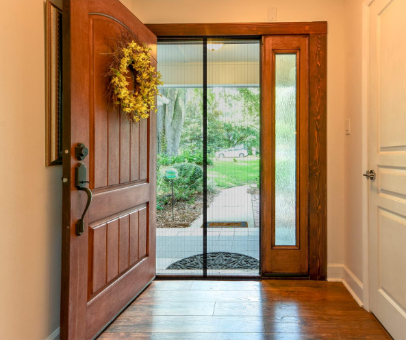 An open front door with wreath, with a magnetic screen door in the doorway.