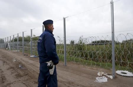 A Hungarian police officer looks on as he stands near a fence at a collection point in Roszke, Hungary September 10, 2015. REUTERS/Laszlo Balogh