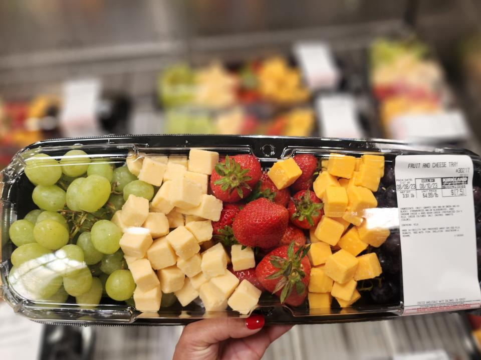 The writer holds a fruit and cheese tray at Costco