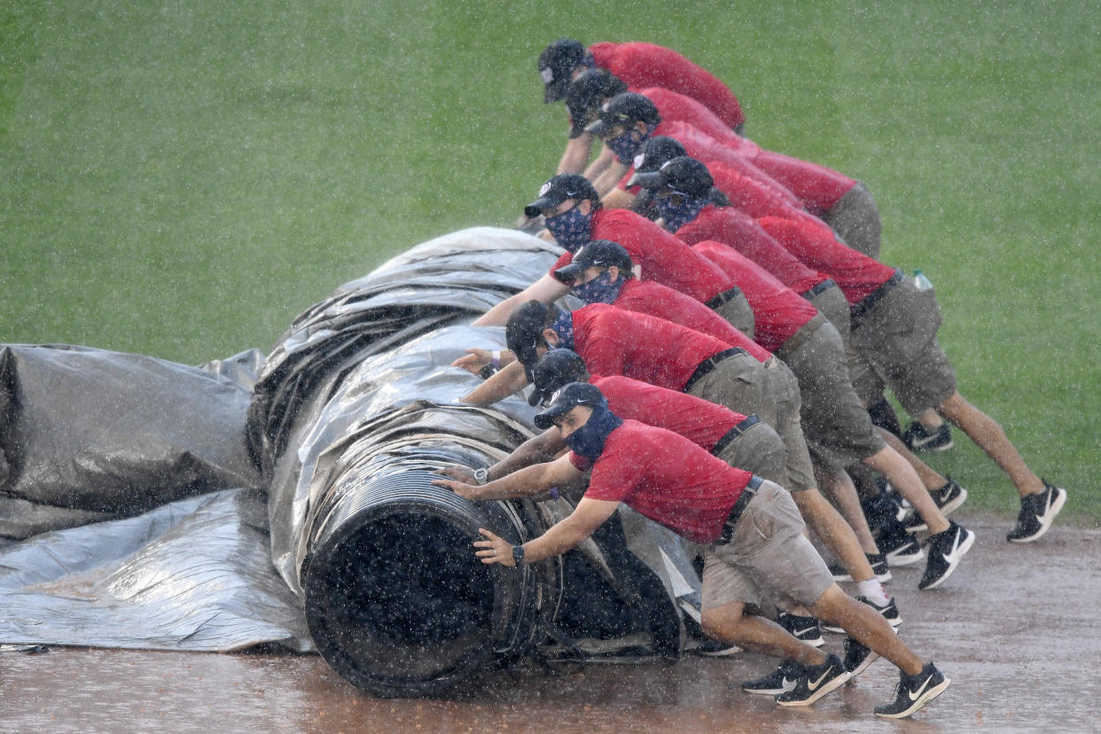 WASHINGTON, DC - AUGUST 09:  The grounds crew tries to cover the field during a rain delay in the fifth inning during a baseball game between the Washington Nationals and the Baltimore Orioles on August 9, 2020 at Nationals Park in Washington, DC.  (Photo by Mitchell Layton/Getty Images)