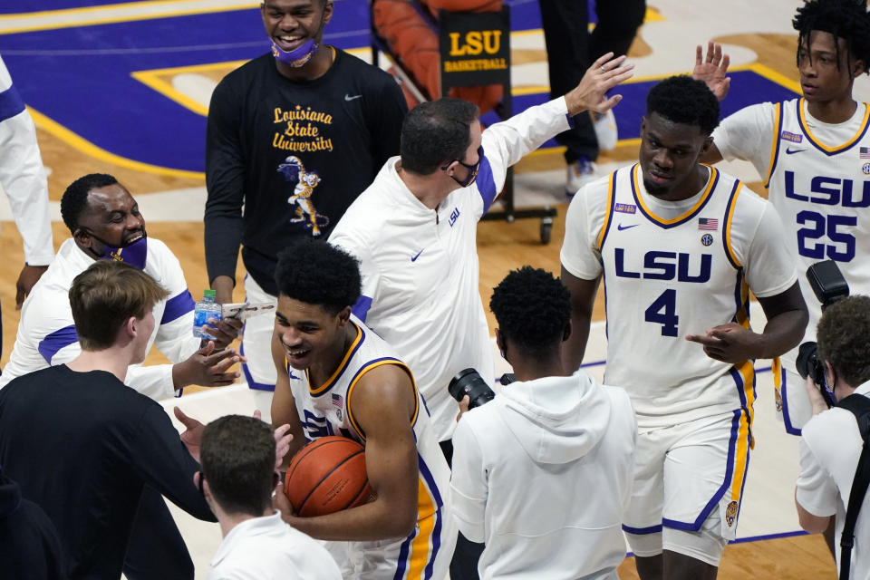 LSU guard Cameron Thomas, holding the ball, celebrates with head coach Will Wade, center, and tamales forward Darius Days (4) and guard Eric Gaines (25) after an NCAA college basketball game in Baton Rouge, La., Saturday, Feb. 13, 2021. (AP Photo/Gerald Herbert)