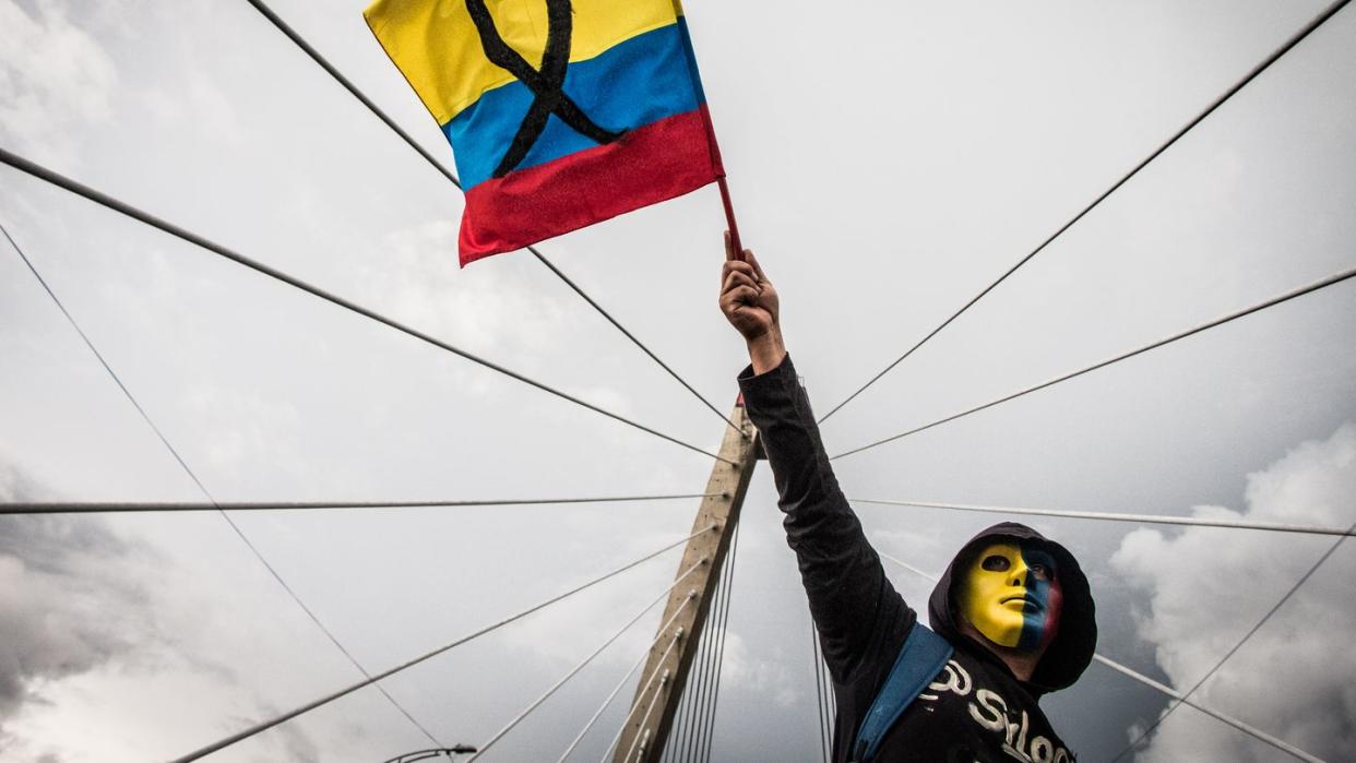 Ein maskierter Demonstrant schwenkt die kolumbianische Flagge.