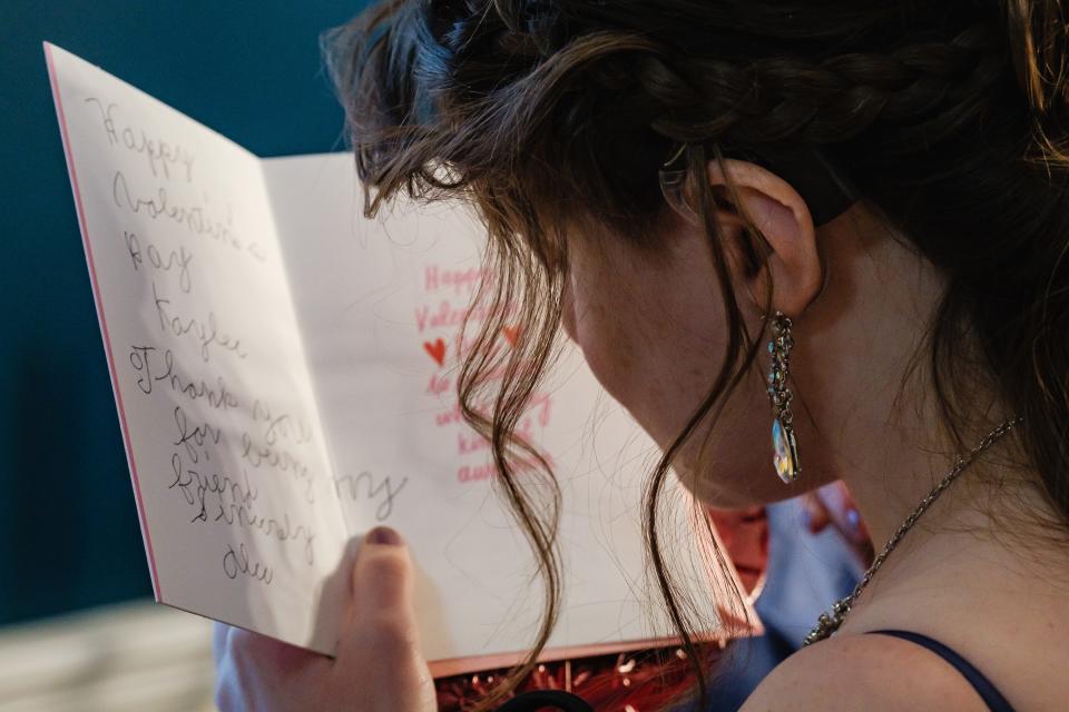 Kaylee Arthurs reads the message Alec Worth wrote on her Valentine's Day card before departing for Night to Shine, a prom for people with special needs, on Friday.