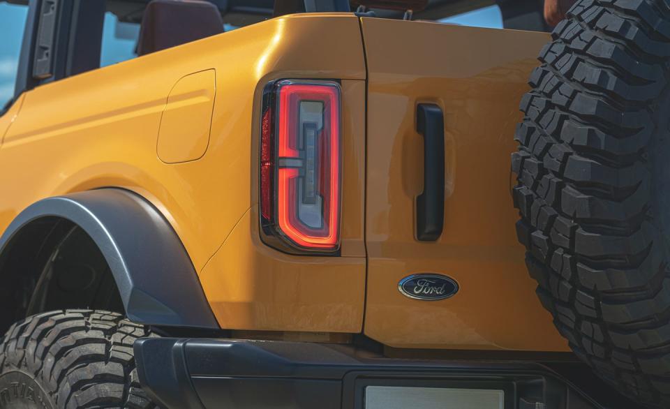 <p>Here the design team nailed a bunch of personality to a baseball bat and beat the new Bronco senseless. Nothing else looks similar, not even the Jeep Wrangler it hopes to defeat. Like the round headlights, its thin vertical taillights are pure Bronco. Unlike earlier Broncos, the new one is chock full of LED lights, but the sharp edges at the bottom of the lights are similar to what the older trucks had. Even the white reverse lamp sits deep inside the housing, like before. The placement of the blue oval at the lower right of the tailgate is also a big 1990s Bronco vibe.</p>