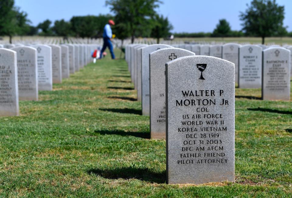 A groundskeeper fertilizes the grass at Texas State Veterans Cemetery at Abilene Tuesday May 19, 2020. In the foreground is the first veteran interred at the cemetery in 2009, Walter P. Morton Jr.