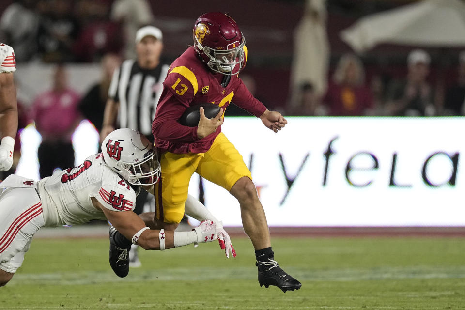 Southern California quarterback Caleb Williams, right, escapes a tackle by Utah linebacker Karene Reid during the second half of an NCAA college football game Saturday, Oct. 21, 2023, in Los Angeles. (AP Photo/Mark J. Terrill)