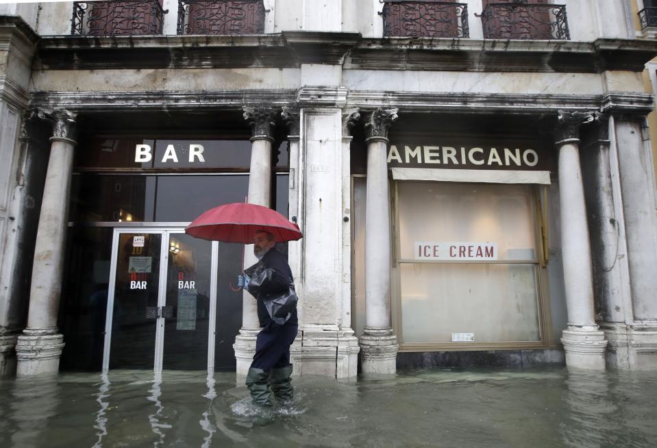 A man walks past a closed cafe in a flooded Venice, Italy, Tuesday, Nov. 12, 2019. (Photo: Luca Bruno/AP)