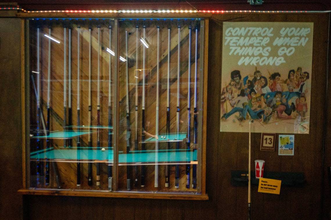 Pool tables are reflected off a glass cabinet holding pool sticks on Thursday at Jointed Cue Billiards.