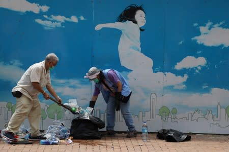 People clean up debris near the Legislative Council building in Hong Kong, China