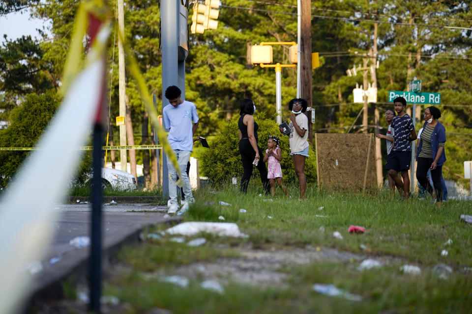 People stand across from the shuttered Xpress Mart Shell station, Friday, June 2, 2023, in Columbia, S.C. Cyrus Carmack-Belton, a 14-year-old boy will be laid to rest less than one week after officials say a South Carolina gas station owner gunned him down in a killing that has prompted cries of racial profiling.(AP Photo/Erik Verduzco)