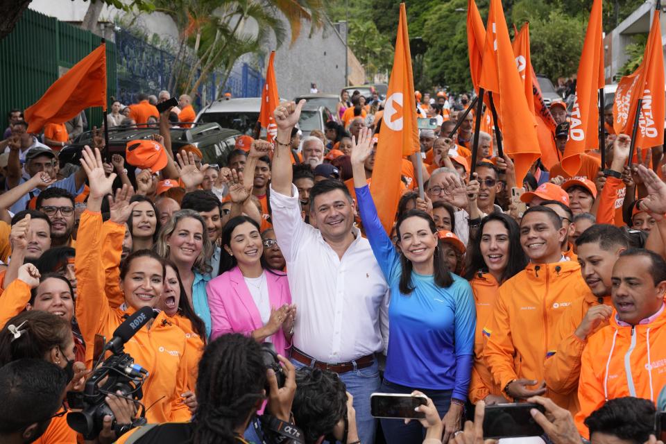 Opposition presidential hopeful Maria Corina Machado, center right, and opposition leader Freddy Superlano, center left, raise their arms for photographers during a campaign event in Caracas, Venezuela, Friday, Oct. 13, 2023. Superlano announced his withdrawal from the primaries and the support of his party, Popular Will, for Machado ahead of opposition primaries to choose one candidate to face President Nicolas Maduro in 2024 general elections. (AP Photo/Ariana Cubillos)