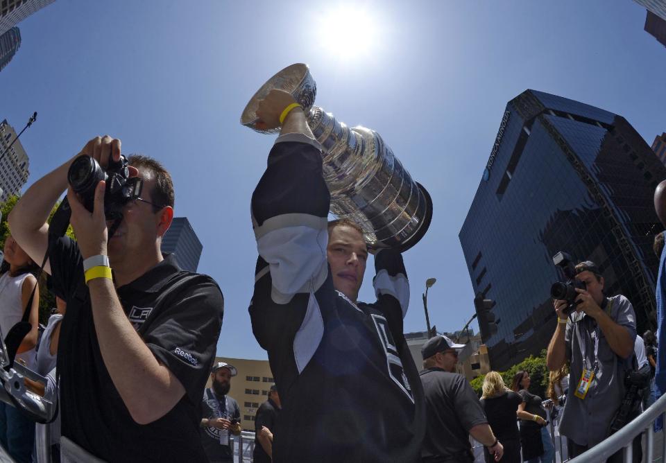 Los Angeles Kings right wing Dustin Brown,center, holds up the Stanley Cup trophy while riding in a parade, Monday, June 16, 2014, in Los Angeles. The parade and rally were held to celebrate the Kings&#39; second Stanley Cup championship in three seasons. The Kings defeated the New York Rangers for the title. (AP Photo/Mark J. Terrill)