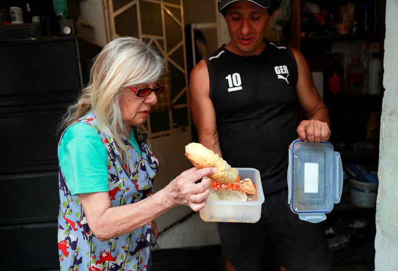 Carlos Alfaro, de 51 años, un conductor de Uber que también es dueño de un negocio de limpieza, le muestra a su madre, Dilcy Marmol, de 77 años, la comida que recibió en una cocina móvil de alimentos administrada por el gobierno, durante la pandemia de la enfermedad del coronavirus (COVID-19), en su casa, en Ciudad de México, México