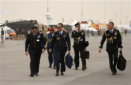 Military visitors walk during the sandstorm at the Dubai Airshow November 17, 2013. REUTERS/Ahmed Jadallah