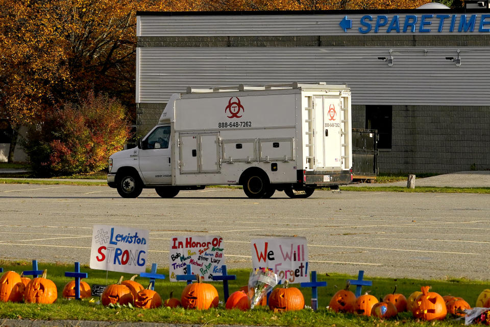 A memorial sit in front of Sparetime bowling as a hazmat crew arrives, Sunday, Oct. 29, 2023, in Lewiston, Maine. The community is working to heal following shooting deaths of multiple people at the bowling alley and a bar in Lewiston on Wednesday. The bowling alley was renamed in 2021 to Just-In-Time Recreation. (AP Photo/Matt York)