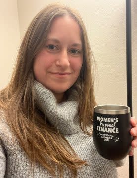 A woman takes a selfie of herself with a coffee mug in her hand.