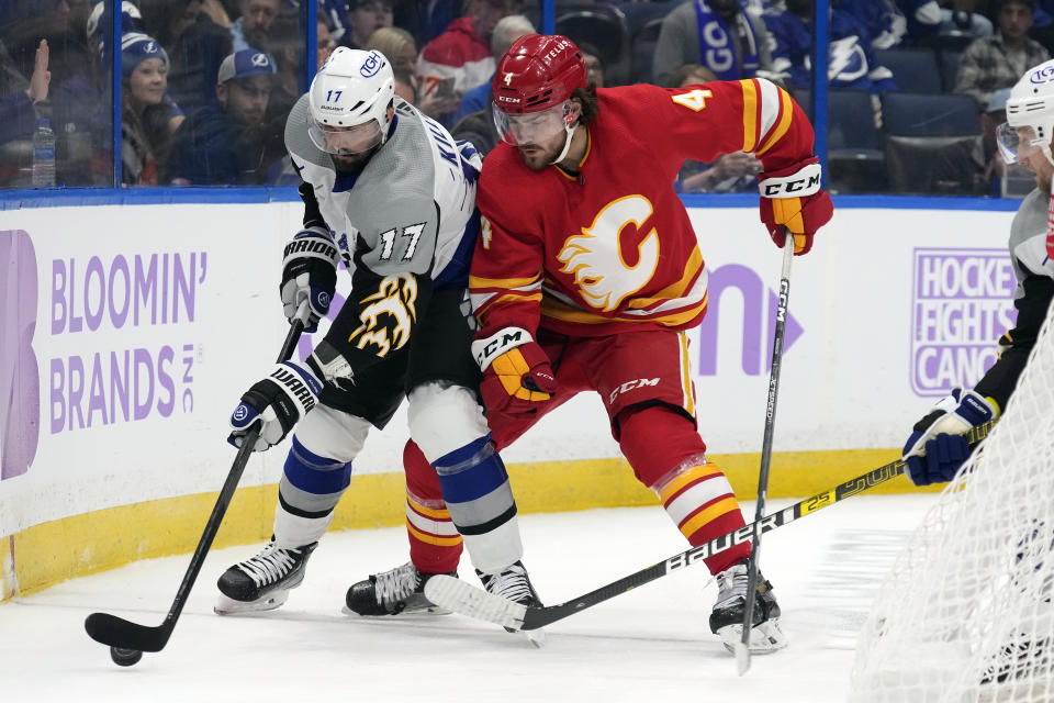 Calgary Flames defenseman Rasmus Andersson (4) pressures Tampa Bay Lightning left wing Alex Killorn (17) as he moves the puck along the dasher during the second period of an NHL hockey game Thursday, Nov. 17, 2022, in Tampa, Fla. (AP Photo/Chris O'Meara)