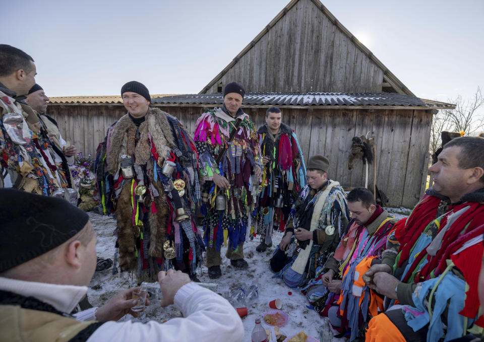 Villagers dressed in traditional costumes, rest , eat and drink while celebrating the Malanka festival in the village of Krasnoilsk, Ukraine, Friday, Jan. 14, 2022. Dressed as goats, bears, oxen and cranes, many Ukrainians rang in the new year last week in the colorful rituals of the Malanka holiday. Malanka, which draws on pagan folk tales, marks the new year according to the Julian calendar, meaning it falls on Jan. 13-14. In the festivities, celebrants go from house to house, where the dwellers offer them food.(AP Photo/Ethan Swope)