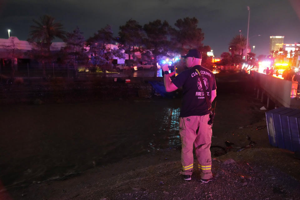 A Clark County Fire Department official searches for people in floodwaters in a flood channel Friday, Sept. 1, 2023, in Las Vegas. (AP Photo/John Locher)