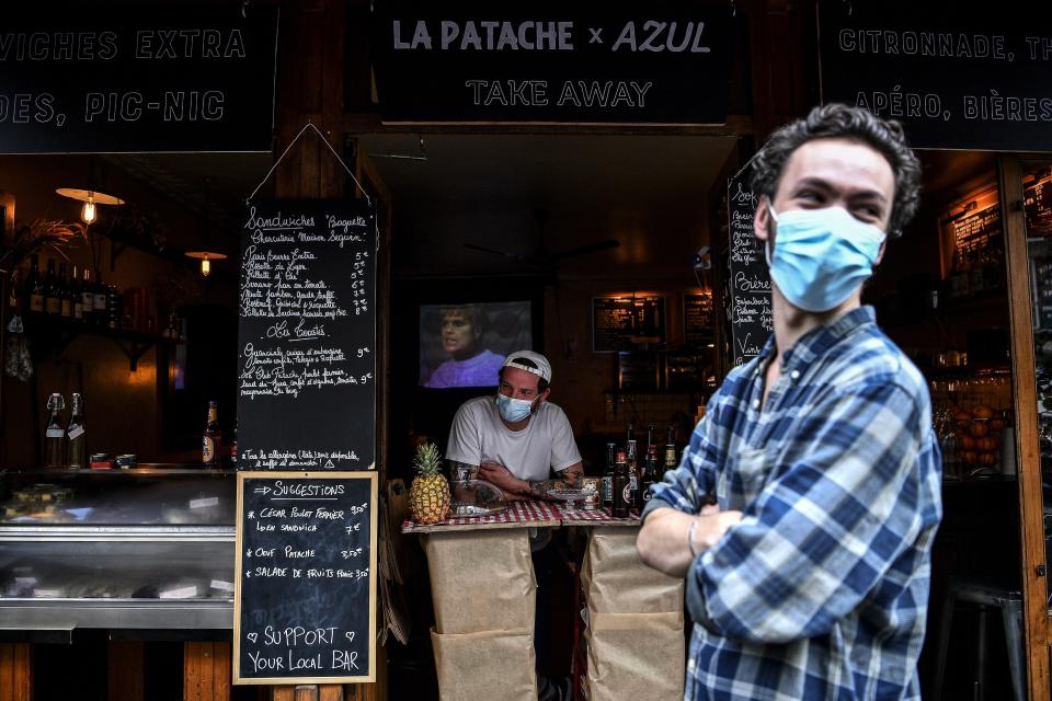 A bartender selling take-away drinks and food waits for customers behind a makeshift counter along the sidewalk in Paris on May 9. (Photo: CHRISTOPHE ARCHAMBAULT via Getty Images)